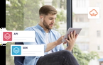 A man using a tablet sits by a large window, wearing earbuds. Overlay icons labeled 'API' and 'SDK' highlight software integration, while a cloud icon suggests cloud-based deployment.